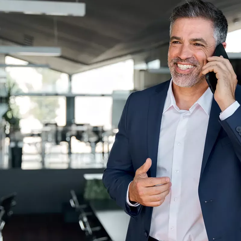 Business man standing talking on phone smiling
