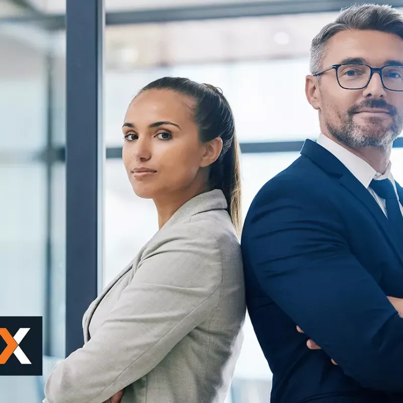 Man and woman dressed in business apparel standing back to back looking at camera