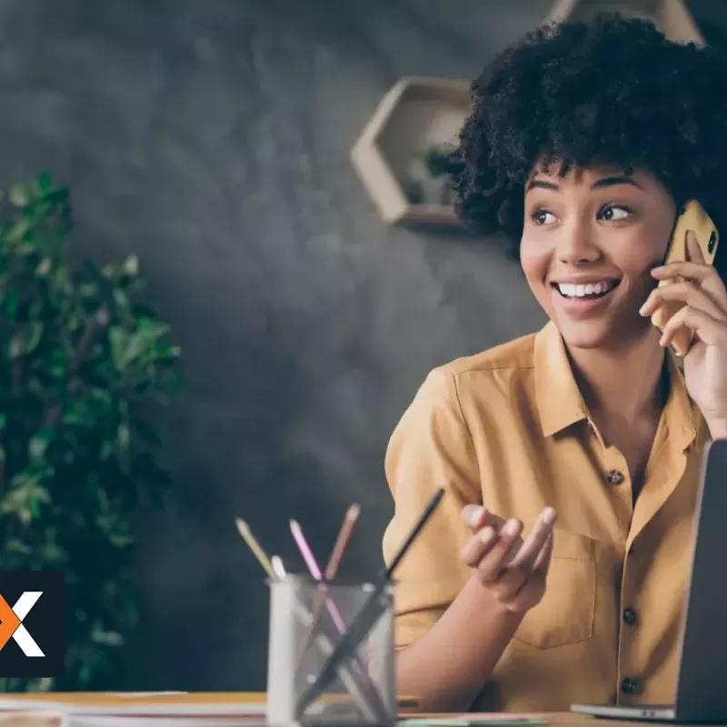 woman sitting at desk with laptop in front of her talking on the phone