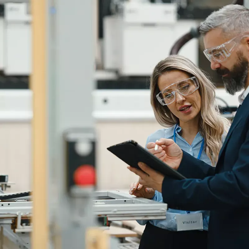 man and woman in eye protectors inspecting a machine 