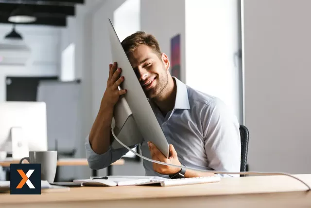 man sitting at desk hugging compuetr