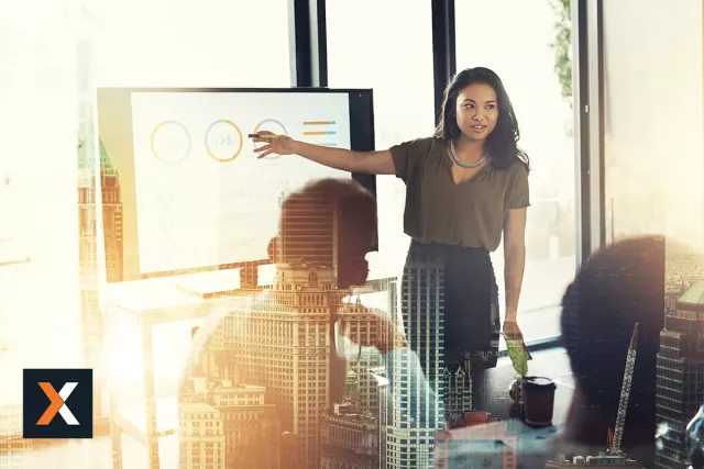 Woman standing presenting at monitor to a group of people