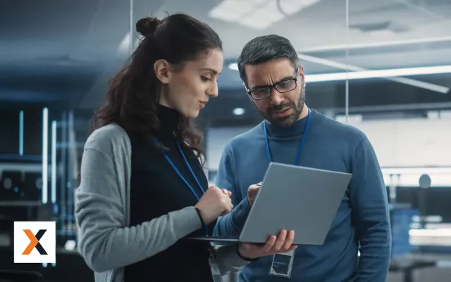 Woman and man standing next to each other looking at laptop together