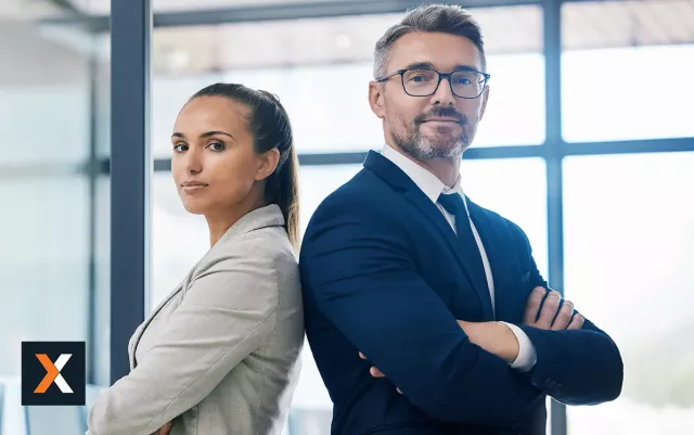 Man and woman dressed in business apparel standing back to back looking at camera