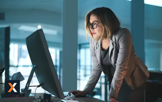 Woman standing at computer desk working 