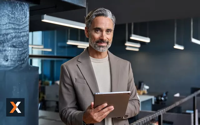 Businessman standing working off tablet smiling at camera