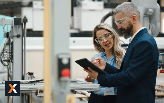 man and woman in eye protectors inspecting a machine 