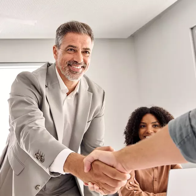 A professional handshake between two men in an office, illustrating a successful business interaction or agreement.