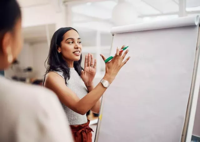 woman standing at writing easel writing and talking to audience