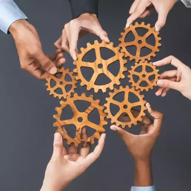 hands holding an art sculpture. the art sculpture is gears turning