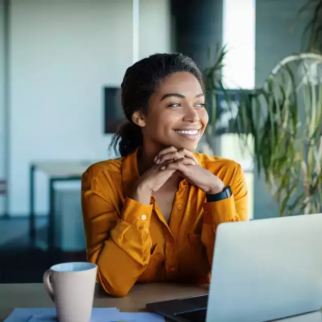 a woman smiling with a work computer in front of her